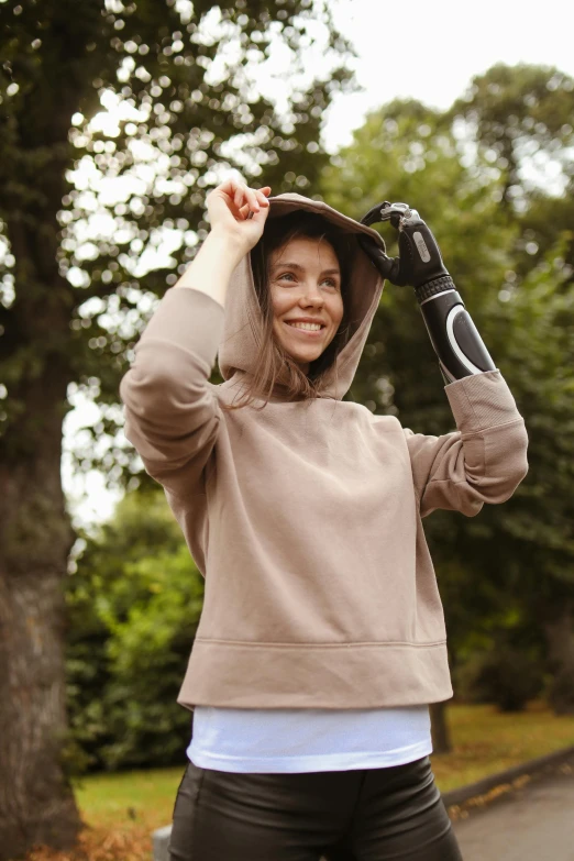 a woman riding a skateboard down a street, a picture, hoody woman explorer, bionic arms and eyes, beige, in the park