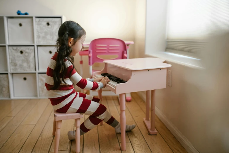 a little girl sitting at a pink piano, pexels contest winner, mingei, with furniture overturned, girl wearing uniform, hand on table, professionally assembled