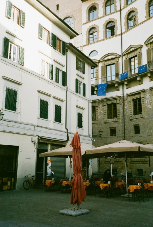 a courtyard with tables and umbrellas in front of a building, inspired by Lattanzio Gambara, pexels contest winner, renaissance, street corner, 1999 photograph, low quality photo, florence