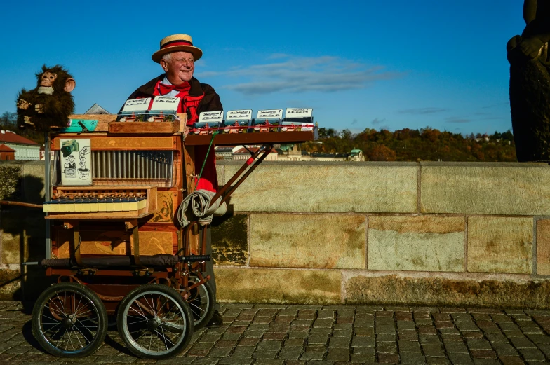 a man that is standing in front of a piano, cart, prague, blue sky, color ( sony a 7 r iv