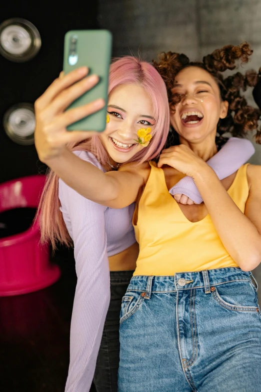 two women taking a selfie with their cell phones, trending on pexels, aestheticism, pink and yellow, lilac hair, college party, promo image