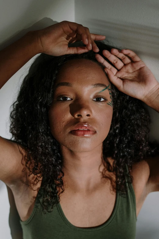 a woman standing against a wall with her hands on her head, by Dulah Marie Evans, trending on pexels, renaissance, green skinned, her face framed with curls, laying on her back on a bed, closeup of sweating forehead