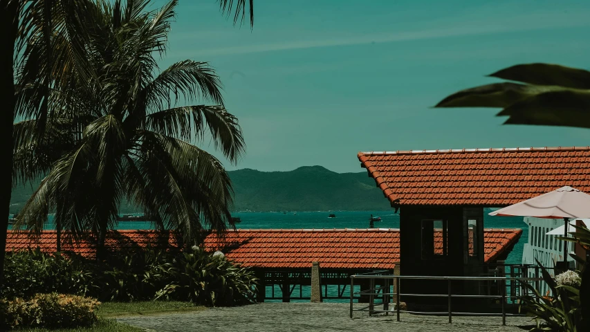 a house sitting on top of a lush green field, pexels contest winner, tropical coastal city, profile image, red building, 70s photo