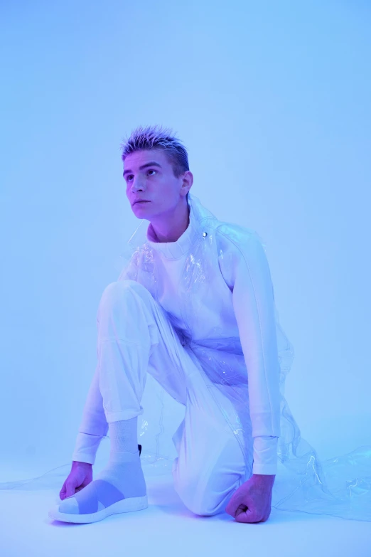 a man sitting on the ground in a white outfit, an album cover, inspired by Kristian Kreković, trending on pexels, neoism, bisexual lighting, “zendaya, shaved sides, cold blue light