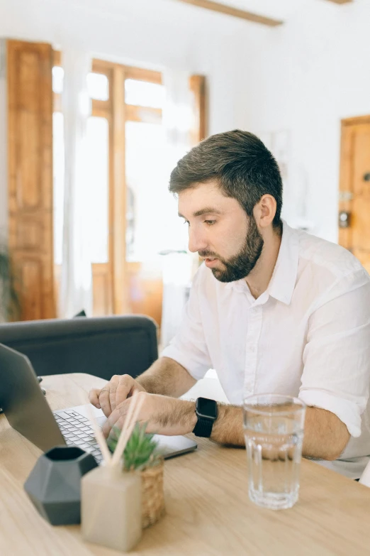 a man sitting at a table working on a laptop, pexels contest winner, wearing a white button up shirt, profile image, thumbnail, caucasian