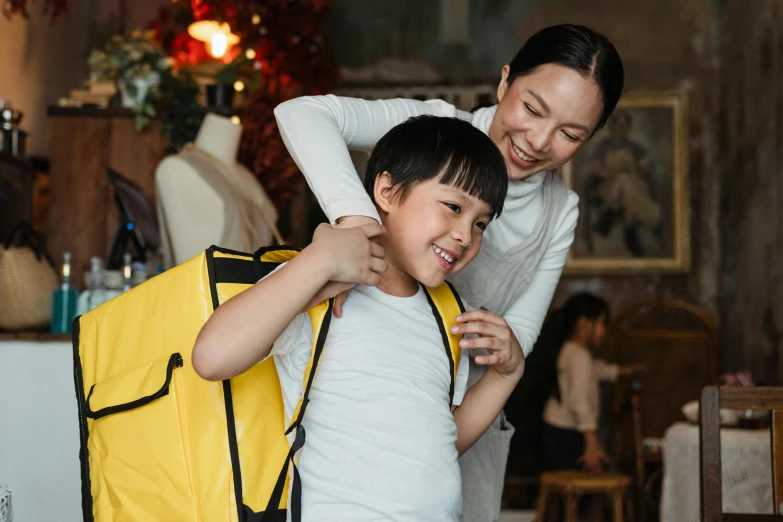 a woman helping a child with a yellow backpack, pexels contest winner, japanese collection product, looking her shoulder, large and tall, holiday season