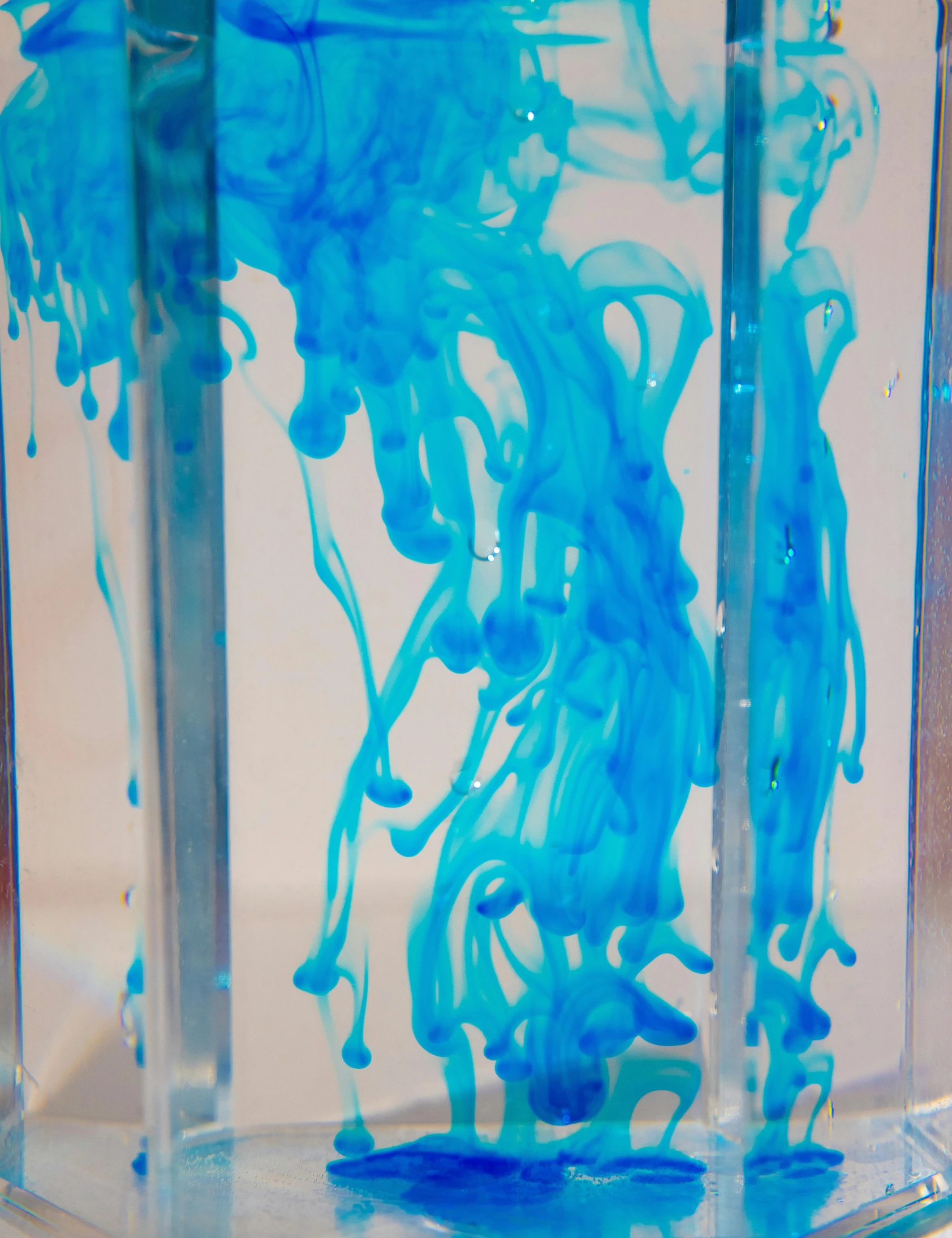 a glass filled with blue liquid sitting on top of a counter, an abstract sculpture, inspired by Yves Klein, unsplash, process art, penned in cyan ink, jellyfish element, medium close - up, ilustration