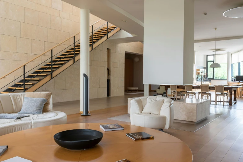a living room filled with furniture and a staircase, inspired by David Chipperfield, unsplash, light and space, beachfront mansion, stone table, bill lowe gallery, bang olufsen