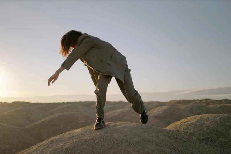 a woman standing on top of a large rock, an album cover, unsplash, figuration libre, wearing human air force jumpsuit, kicking up dirt, julian ope, still frame from a movie