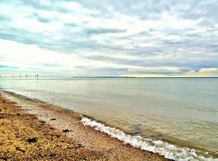 a large body of water sitting on top of a sandy beach, an album cover, overcast skies, body of water, bay, highfleet