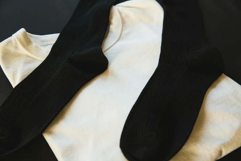 a pair of black socks sitting on top of a white shirt, unsplash, renaissance, bottom body close up, various sizes, ( ivory black ), detached sleeves