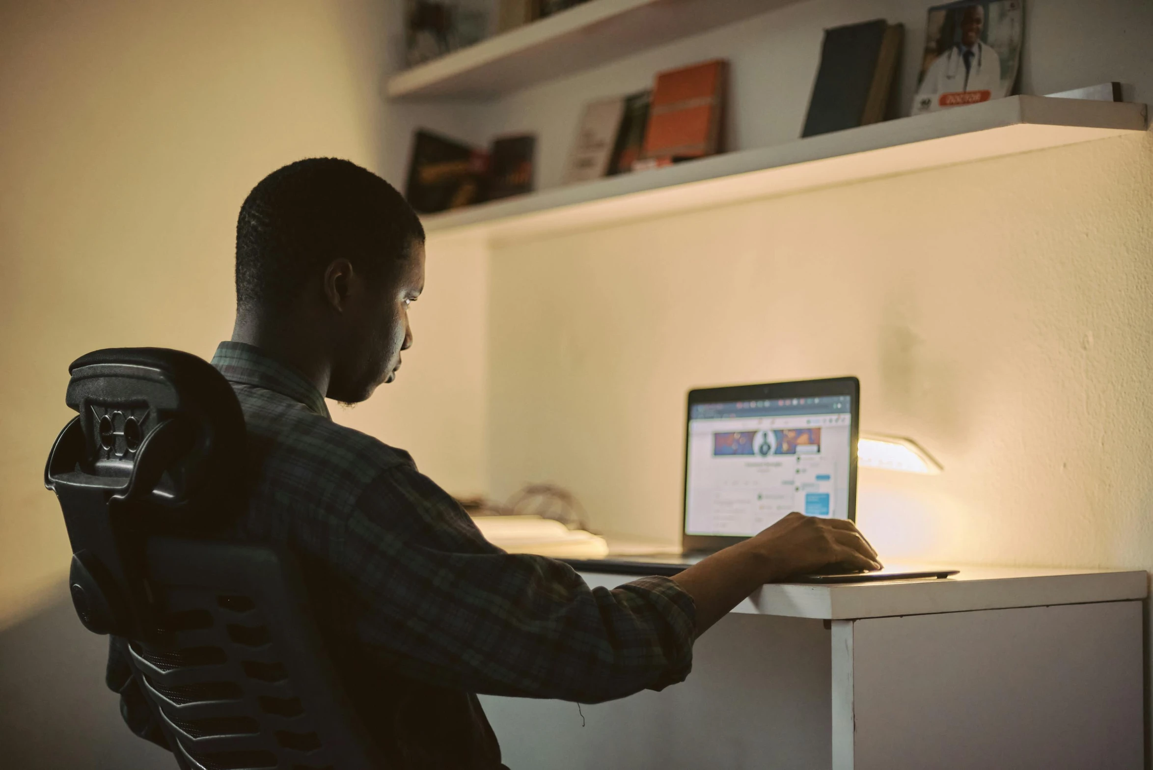 a man sitting at a desk using a laptop computer, pexels contest winner, lights off, ashteroth, carson ellis, ignant