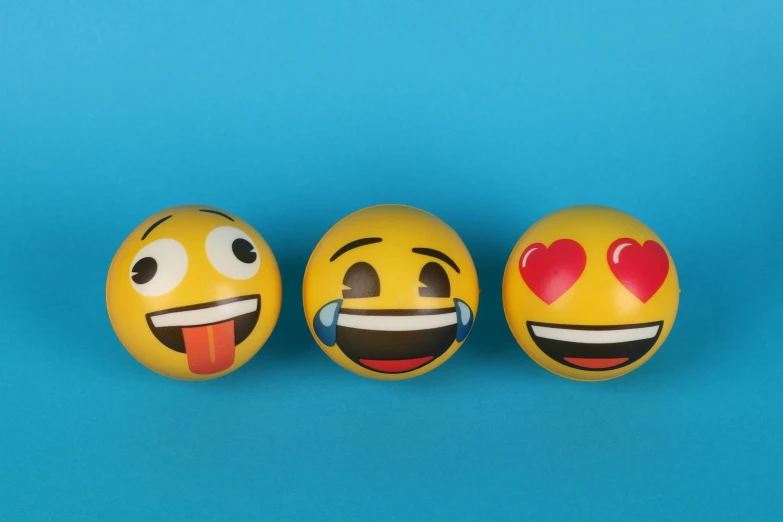 three yellow emoticions on a blue background, by Elaine Hamilton, trending on pexels, 3 d print, spheres, kiss, ios emoji