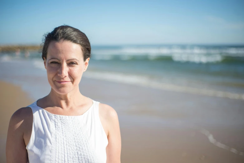 a woman standing on a beach next to the ocean, a portrait, profile image, manuka, portrait image, group photo