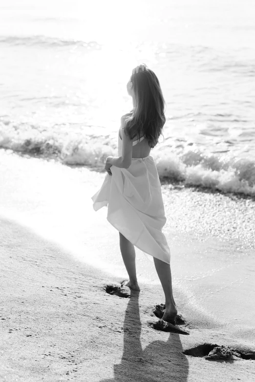 a black and white photo of a little girl on the beach, a black and white photo, tumblr, renaissance, a beautiful woman in white, about to step on you, profile image, alternate album cover