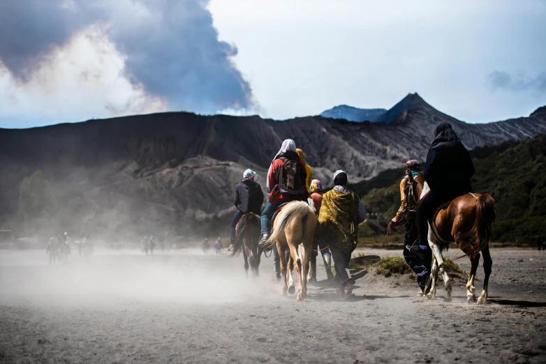 a group of people riding on the backs of horses, a photo, by Julia Pishtar, trending on unsplash, sumatraism, volcanic eruption, gunfire, poop, movie set”