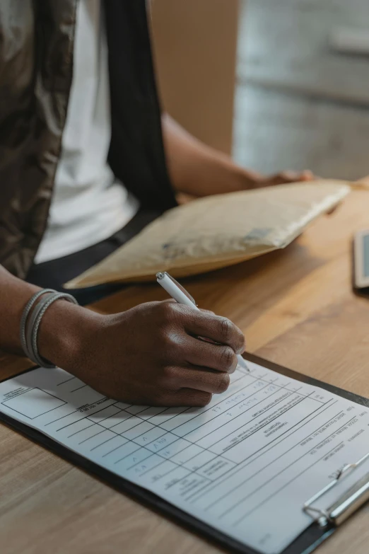 a person sitting at a table writing on a piece of paper, clipboard, register, curated collections, high quality photo