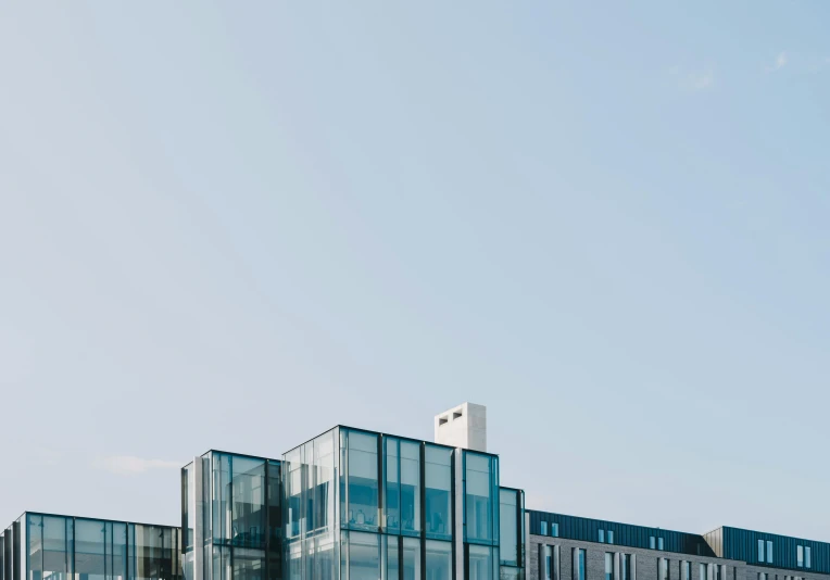 a large building sitting on top of a lush green field, inspired by Richard Wilson, unsplash, modernism, clear glass wall, ten flats, clear blue skies, reykjavik