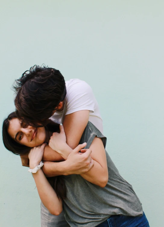 a man and a woman hugging in front of a wall, trending on unsplash, woman holding another woman, romantic lead, plain background, 15081959 21121991 01012000 4k