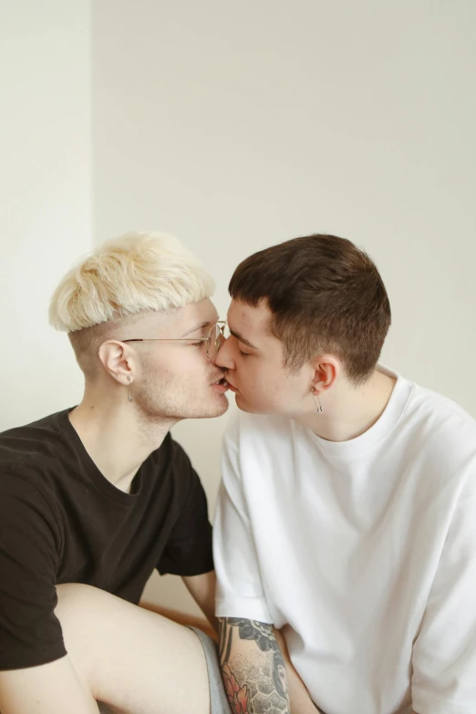 a couple of men sitting on top of a bed, by Cosmo Alexander, trending on pexels, albino hair, kissing each other, on a white table, he is about 20 years old | short
