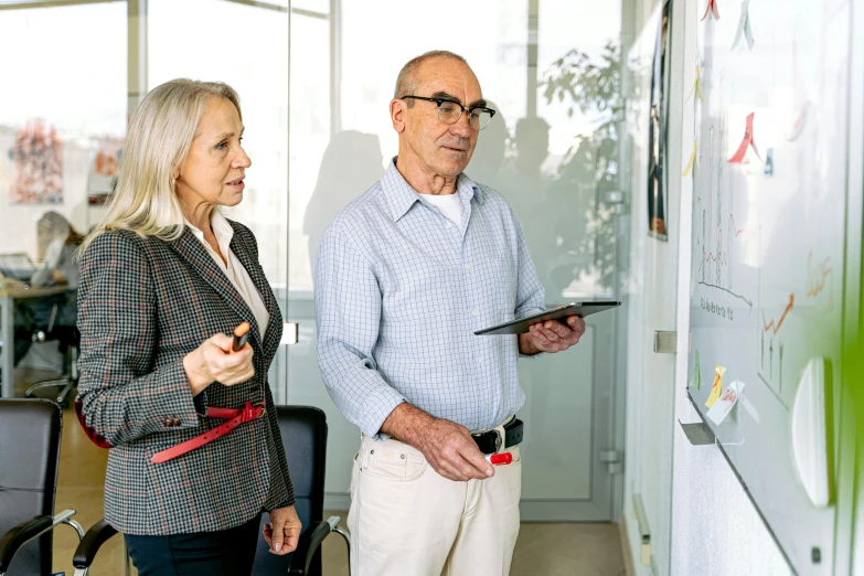 a man and a woman standing in front of a whiteboard, older male, people at work, profile image, advanced