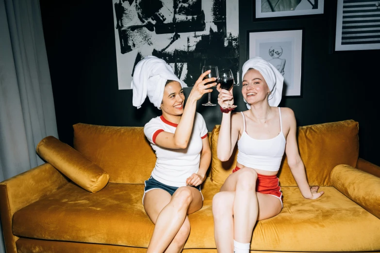 a couple of women sitting on top of a couch, by Julia Pishtar, pexels, renaissance, wearing a white bathing cap, nightlife, themed after wine, sydney sweeney