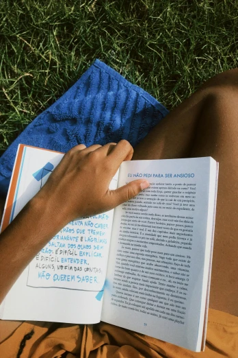 a person laying on the grass reading a book, wearing a towel, in spain, blue print, up close