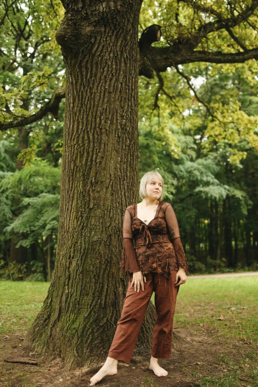 a woman standing next to a large tree, an album cover, inspired by Jane Nasmyth, renaissance, green and brown clothes, press shot, marthe jonkers, panorama