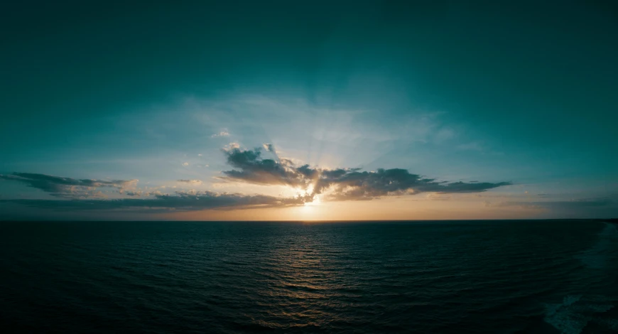 the sun is setting over the ocean, by Alexander Bogen, pexels contest winner, teal sky, wide angle shot from above, high-quality photo, slightly pixelated