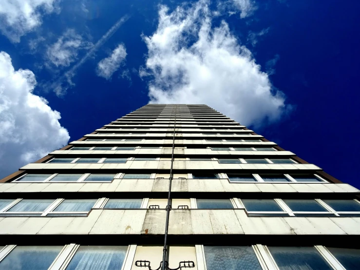 a tall building with a blue sky in the background, inspired by Richard Wilson, unsplash, brutalism, ten flats, high clouds, lit from below, very high view