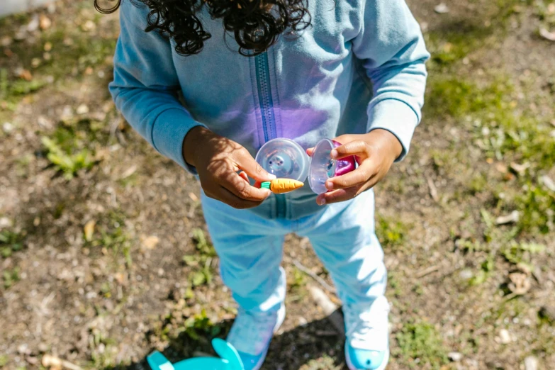 a little girl standing on top of a grass covered field, a child's drawing, by Julian Allen, pexels contest winner, graffiti, iridescent soapy bubbles, wearing a purple sweatsuit, holding a candle holder, wearing a neon blue hoodie