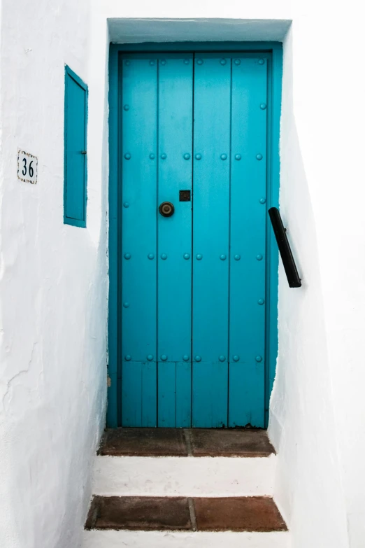 a blue door sitting on the side of a white building, inspired by Josep Rovira Soler, turquoise, marbella, lock, teal