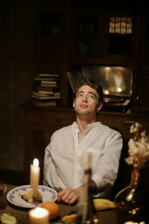 a man sitting at a table with a plate of food, inspired by Pierre Brissaud, trending on reddit, renaissance, dramatic lighting; 4k 8k, wearing a light shirt, candlelight, handsome face