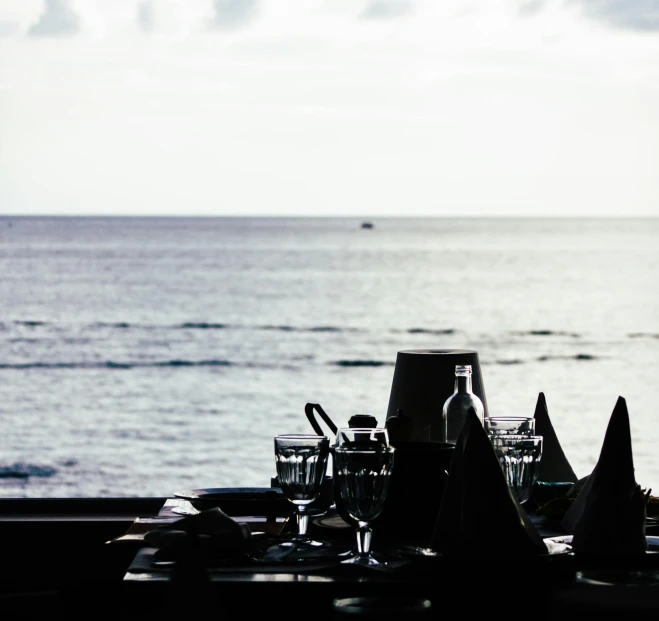 a table setting with a view of the ocean, a still life, unsplash, silhouetted, black, long