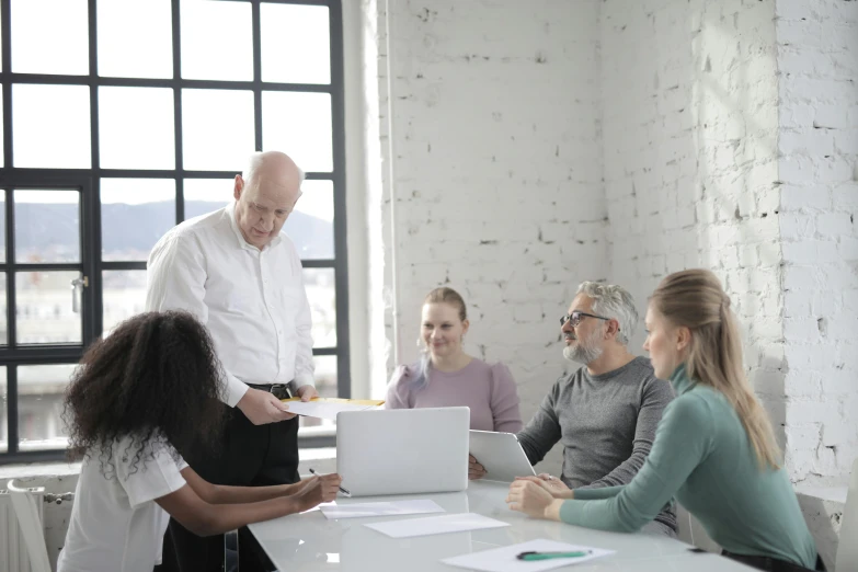 a group of people sitting around a table with a laptop, on a white table