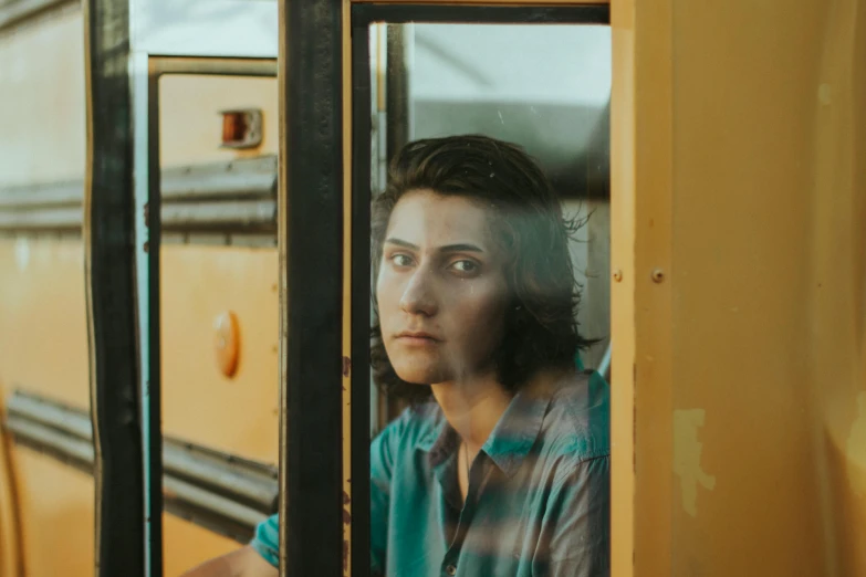 a woman looking out the window of a school bus, a portrait, pexels contest winner, non-binary, looking serious, shot from movie, elizabeth saltzman