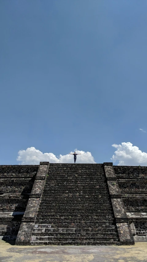 a person standing on top of a pyramid, by Matteo Pérez, aztec architecture, blue sky, over-shoulder shot, high quality photo