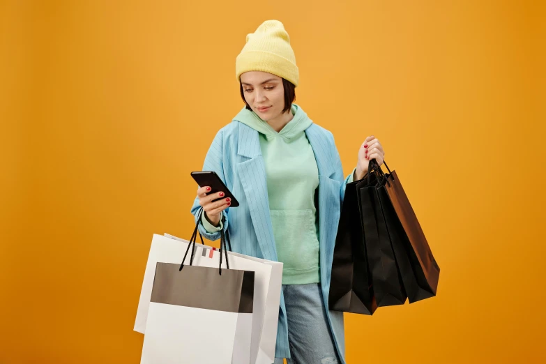 a woman holding shopping bags and looking at her phone, trending on pexels, maximalism, wearing a yellow hoodie, avatar image, professional photo, maisie williams