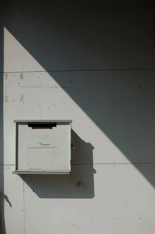 a white box sitting on the side of a building, an album cover, unsplash, bee, brutalist appearance, back light, ignant