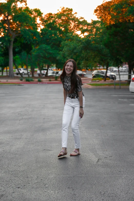 a woman standing on a skateboard in a parking lot, wearing a shirt and a jean, white pants, asher duran, profile image