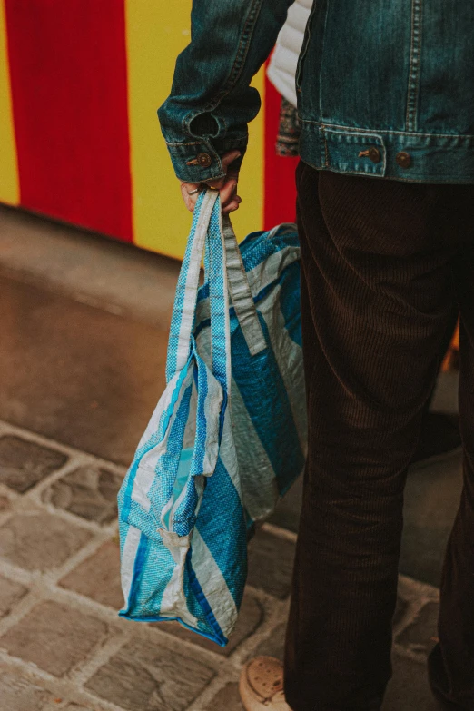 a person carrying a blue and white bag, by Nina Hamnett, pexels contest winner, arte povera, in paris, recycled, ribbon, vibrant glow