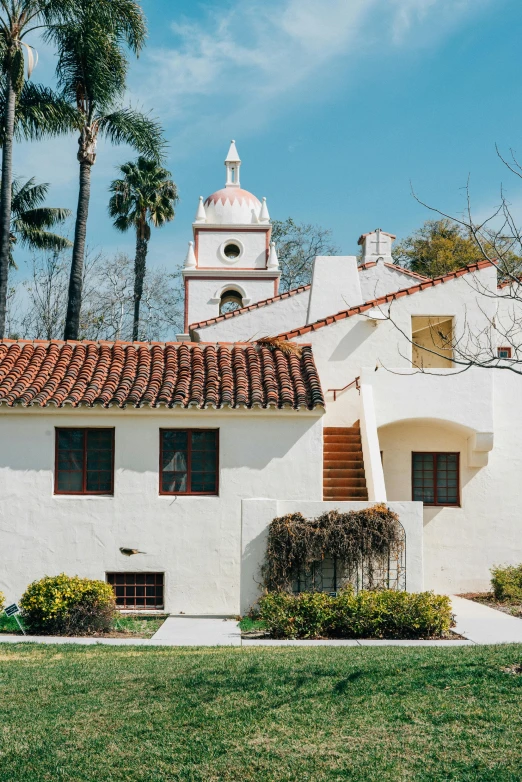 a white building sitting on top of a lush green field, the city of santa barbara, stucco walls, colonial exploration, crisp clean shapes