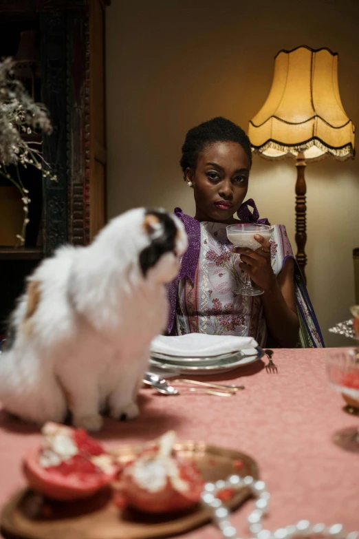 a woman sitting at a table with a cat, lupita nyong'o, regency-era, holiday season, square