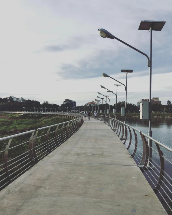 a walkway next to a body of water, by Alejandro Obregón, patiphan sottiwilaiphong, in the middle of the city, low quality photo, stainless steal