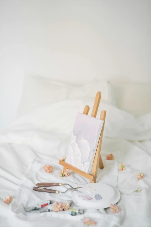 a painting easel sitting on top of a bed covered in white sheets, inspired by Anton Mauve, pexels contest winner, 9 0 mm studio photograph tiny, heavenly marble, white backdrop, portrait of a small