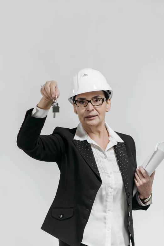 a woman in a hard hat holding a piece of paper, wearing a suit and glasses, holding a wrench, 2019 trending photo, older woman