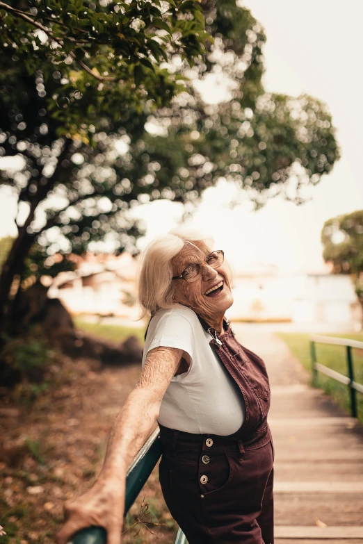 a woman holding a frisbee on a wooden walkway, pexels contest winner, happening, old lady screaming and laughing, paul barson, happily smiling at the camera, in a city park