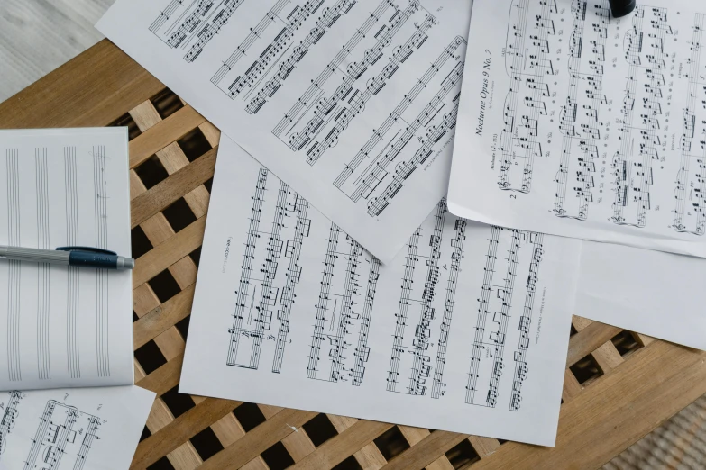 a pile of sheet music sitting on top of a wooden table, unsplash, set pieces, on vellum, thumbnail, multiple stories