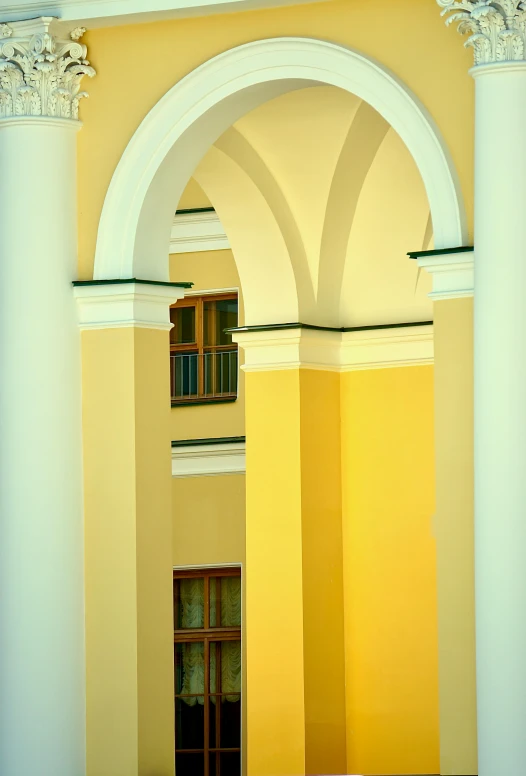 a clock mounted to the side of a yellow building, inspired by Osman Hamdi Bey, academic art, arches adorned pillars, colors: yellow, hallways, kremlin