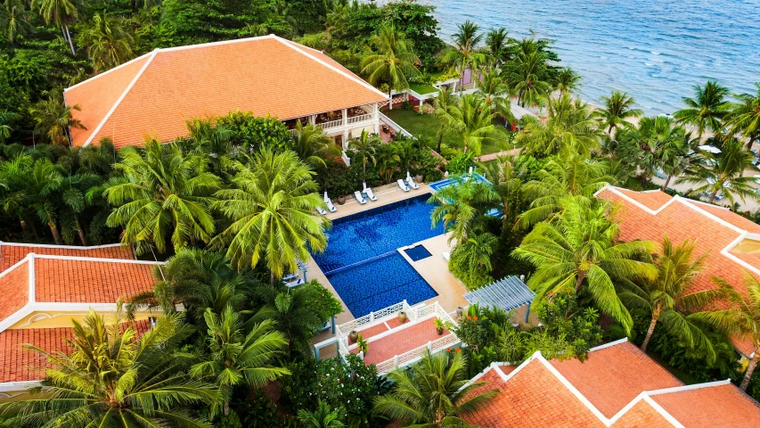 an aerial view of a resort surrounded by palm trees, a portrait, fine art, cambodia, swimming pool in front, beachfront mansion, vibrant greenery outside